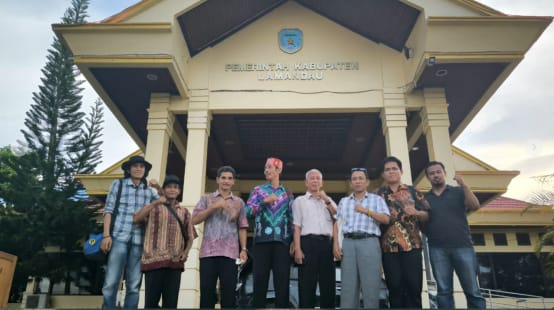 Acht Bürger aus Kinipan vor einem Eingang mit der Aufschrift "Regierung des Bezirks Lamandau"