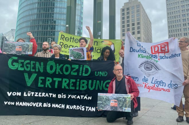 Eine Gruppe von Personen protestiert mit grossen farbigen Bannern vor drei Bürohochhäusern