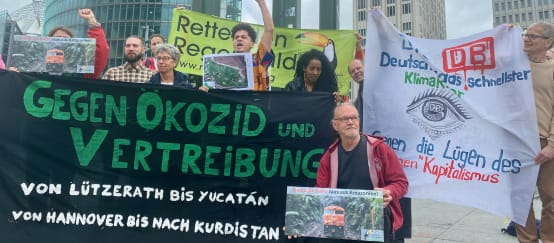 Eine Gruppe von Personen protestiert mit grossen farbigen Bannern vor drei Bürohochhäusern