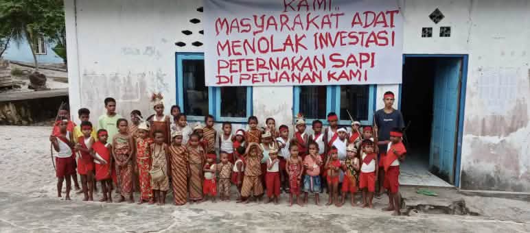 "Wir Indigenen lehnen Investitionen in Rinderzucht auf unserem Land ab!" Kinder vor Schule mit Banner "Wir Indigenen lehnen Investitionen in Rinderzucht auf unserem Indigenenland ab"