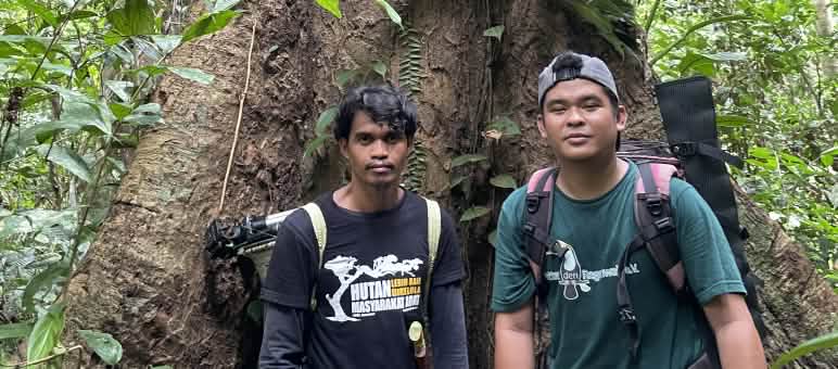 M Habibi (links) und Jahrul von Save our Borneo Habibi und Jahrul von SOB vor einem Baum im Regenwald