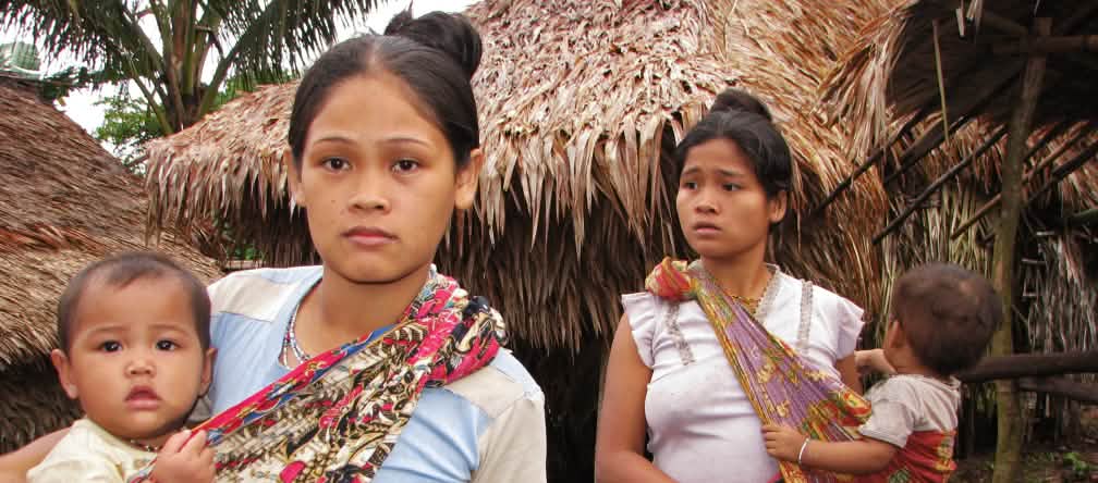 „Die Zukunft unserer Kinder ist der Wald. Plantagen machen uns arm", so die Frauen der indigenen Palawan 2 Frauen mit ihren Kindern vor strohgedeckten Häusern