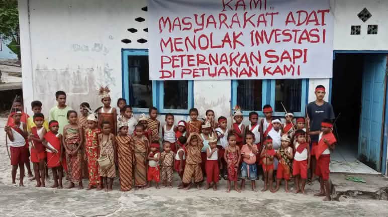 "Wir Indigenen lehnen Investitionen in Rinderzucht auf unserem Land ab!" Kinder vor Schule mit Banner "Wir Indigenen lehnen Investitionen in Rinderzucht auf unserem Indigenenland ab"